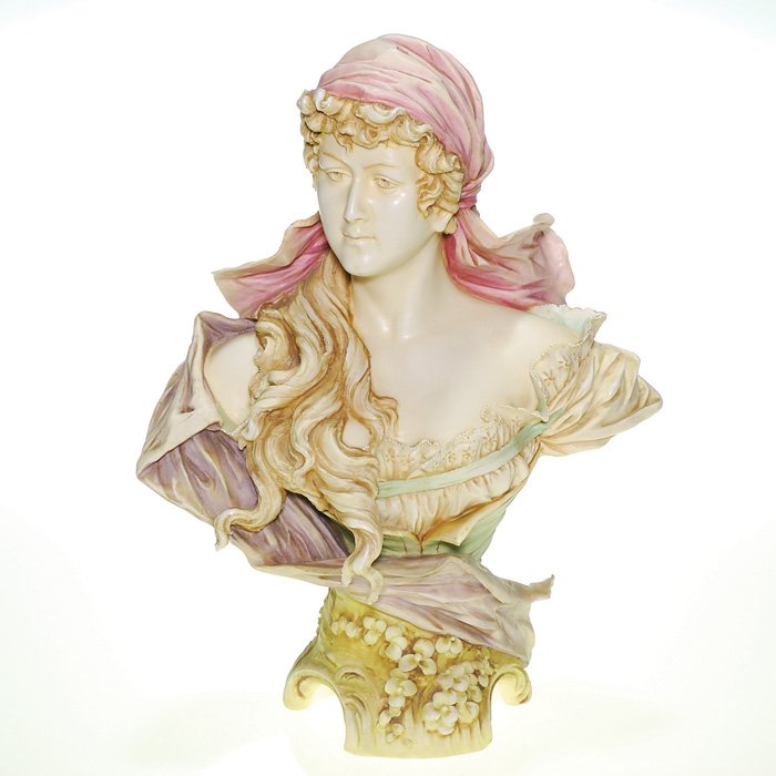 Amphora Art Nouveau female bust, 14”: Amphora Art Nouveau porcelain bust of a maiden with dreamy intaglio eyes, her head capped with lengthy dreadlocks spilling over her bare shoulder and wearing an off-shoulder eyelet bodice. Applied flo