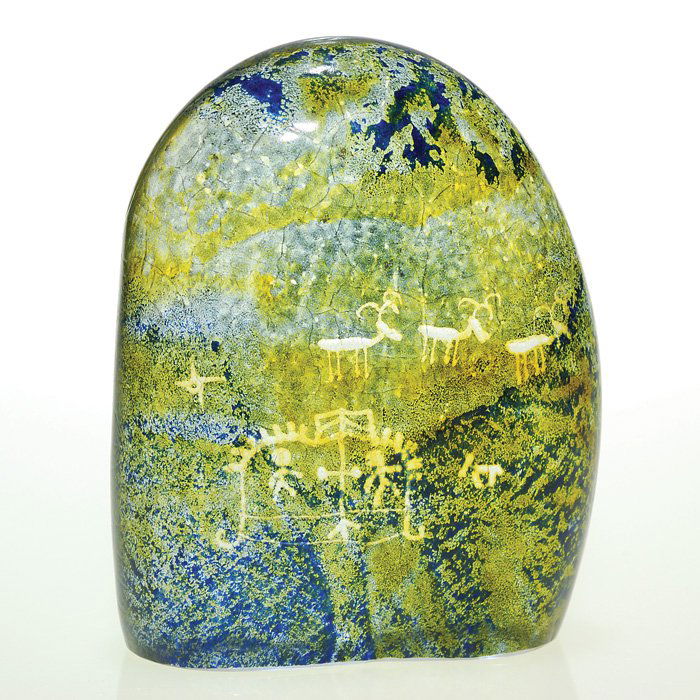 Kosta, Warff “cave art” sculpture, 4 5/8”, signed: Kosta sculpture by artistian Goran Warff featuring “cave art” of humans and animals wheel engraved over a textured stone-like surface and covered with yellow and blue enameling. Height 4 5/8 inche