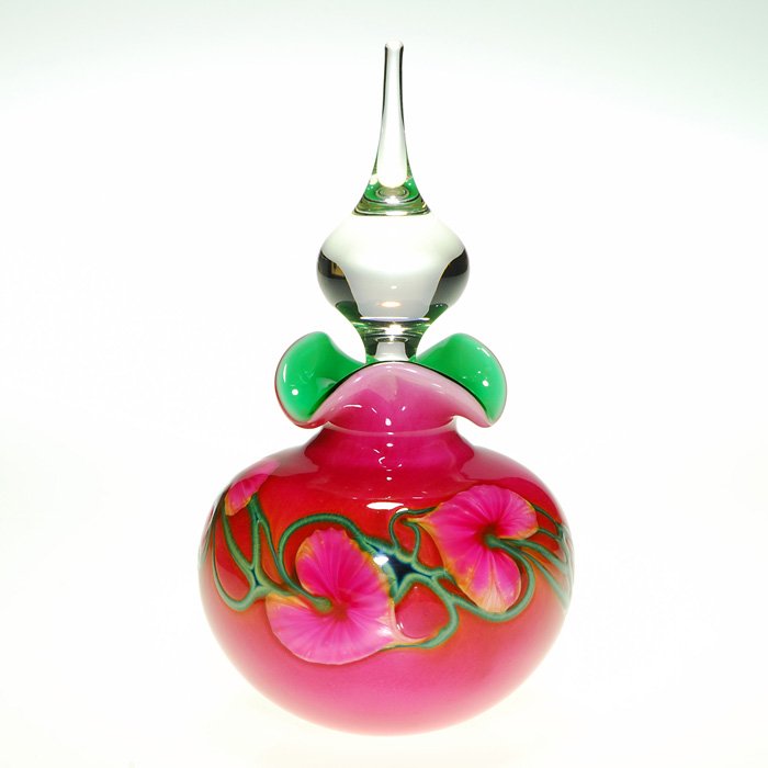 Jerry Heer, Lotton cologne, teardrop stopper, 8”, sig: Beautiful Jerry Heer, Lotton Studios cologne bottle with pink and green leaves and vines against orange pink. A clear teardrop stopper settles within a tri-ruffled rim exposing a complementary bright