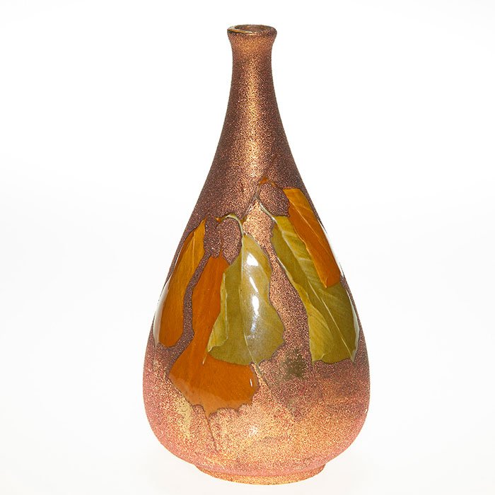 Owens Opalesce Utopian vase, leaves, 7 3/4”: Owens Opalesce Utopian 7 3/4 inch vase with green orange high glaze leaves set against a rich coppery opalescent ground. Height is 7 3/4 inches. Marked Owens and shape 817 on bottom. There is very min