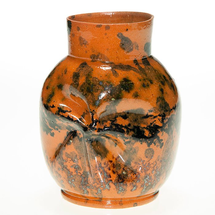 George Ohr twist vase, orange-black glaze, 5 1/4”: Good George Ohr vase with slightly twisted body with faces on opposing sides and an interesting application of green and black splotches on the orange clay body, all covered with a clear high glaze. I