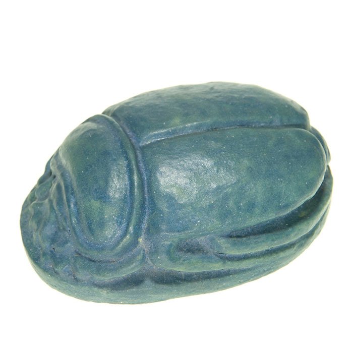 Grueby scarab paperweight, blue, 1 1/4” x 3 1/4”: Grueby scarab paperweight covered with blue over green mat glazes. Impressed with the circular Grueby Faience logo on the base. Size is 1 1/4 inches high and 3 1/4 inches long. There is one tiny glaze