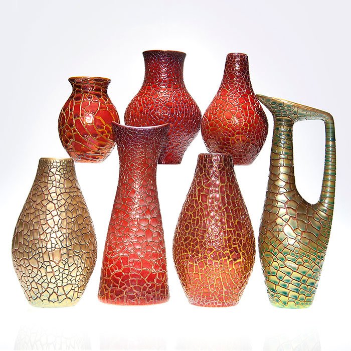 7 Zsolnay Crackleware: 6 assorted vases, 1 pitcher: Group of seven Zsolnay pieces, 6 vases and one pitcher, all having a crackled luster finish. There are five red luster vases in the following sizes: 5 1/4”, 7”, 7 1/4”, 9” and 10 7/8”. There
