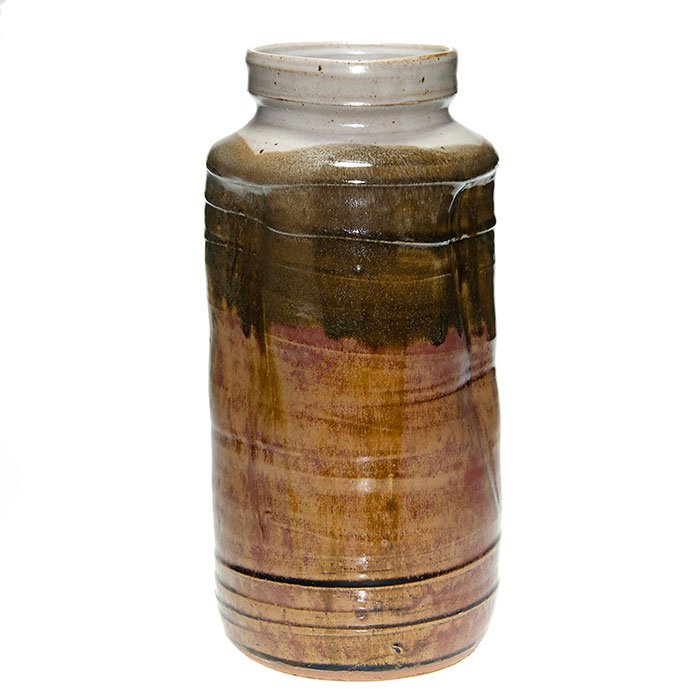 Warren MacKenzie thrown, pinched vase, 14 3/8”: Tall Warren MacKenzie thrown and pinched vase marked with concentric horizontal lines and covered with a mottled gray over brown glaze combination. Marked with the artist’s touch mark at the base. H