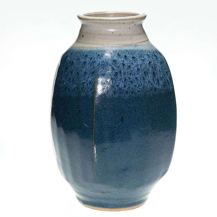 Warren MacKenzie faceted vase, 12 7/8”: Warren MacKenzie thrown vase with flattened sides done in a gray-brown over variegated blue high glaze. Singed with the artist’s touch mark where the side meets the base. Height 12 7/8 inches. Excel