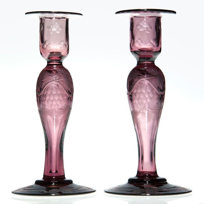 Pr Pairpoint candlesticks, amethyst, carved, 7 7/8”: Pairpoint pair candlesticks in amethyst, wheel carved with grapes on the vine, leaves on the stems, vines on the bases and beaded patterns on the holders. Height 7 7/8 inches. Elegant and in excellent