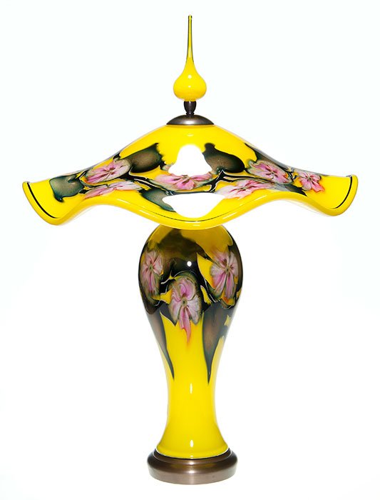 Charles Lotton Mandarin Yellow lamp, 28 3/4”, sign: Impressive Mandarin Yellow Multi-Flora lamp created from the gifted hands of Charles Lotton. A combined total of 20 pinky white flowers in wreath fashion with lots of green foliage bound by blackened