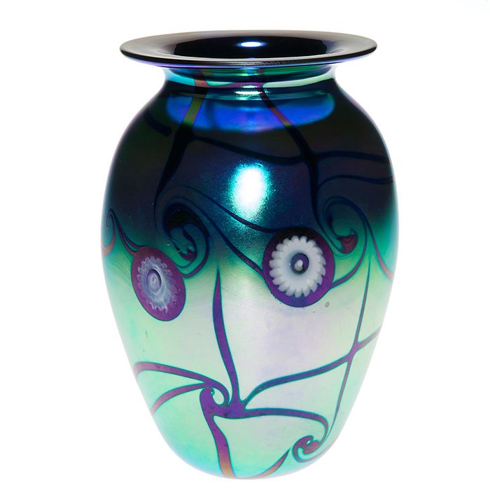 Robert Eickholt vase, millefiori, aurene blue, 6”: Robert Eickholt blue aurene vase decorated with white millefiori “cog” flowers floating among dark coiled tendrils. Height 6 inches. Engraved by the artist with a 2001 date and VCM. Beautiful pink