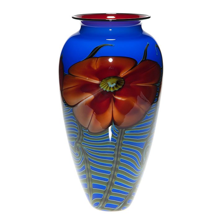 Satava vase, red flower, ferns, 12”, signed, ‘95: Large vase, the creation of Richard Satava featuring homogenous red peachy blossoms backed by fronds of ferns against a royal blue backdrop. Scarlet red cases the interior and a black lip wrap finishe