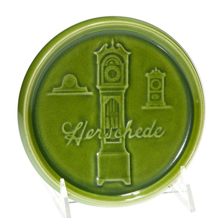 Rookwood “Herschede” tray, 1963, 5 5/8” diameter: Uncommon advertising tray made in 1963 by Rookwood in Starkville for its parent company, the Herschede Hall Clock Company. Pictured in relief are three of Herschede’s clocks all under a 1960’s Ave