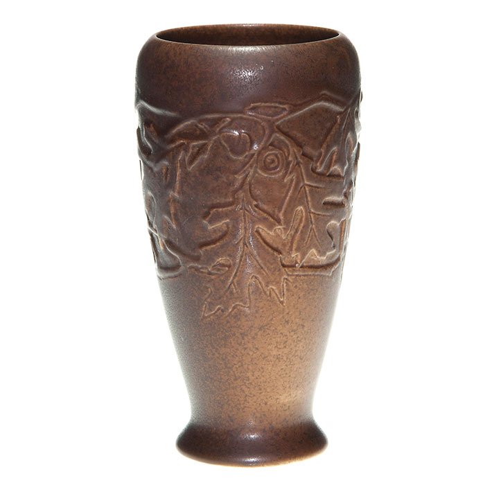 Rookwood mat Production vase, oak leaves, 7 5/8”: Rookwood production vase with molded oak leaf design, cast in 1925 and covered with a deep brown mat glaze. Marks include the Rookwood logo, date and shape 2590. Height is 7 5/8”. There is one 1/4��