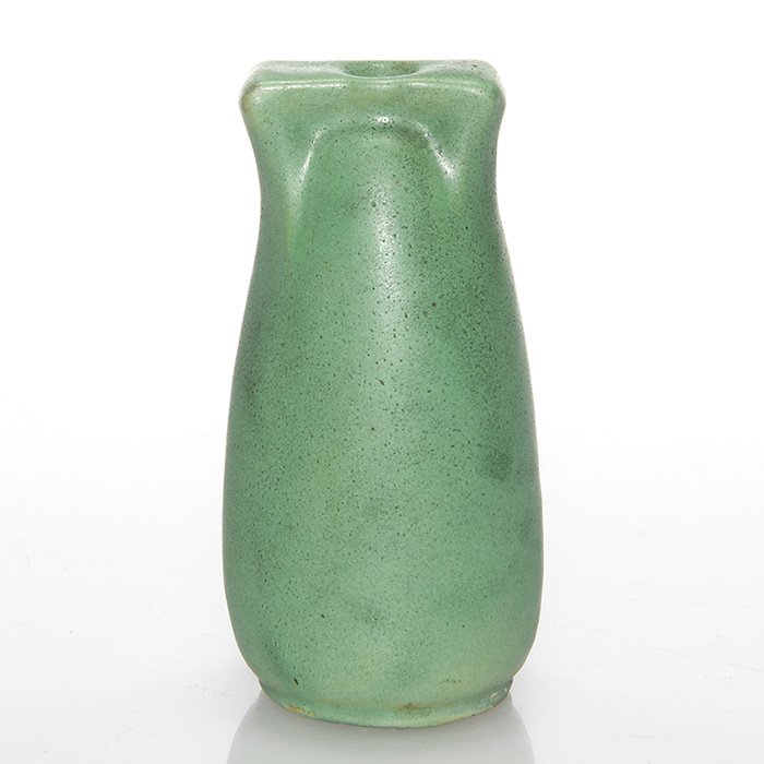 Tiny Teco bud vase: Teco miniature bud vase covered in a green mat glaze with hints of charcoaling. Uncrazed. Height is 3 1/8 inches. Glaze has run over onto the bottom obscuring the Teco mark.