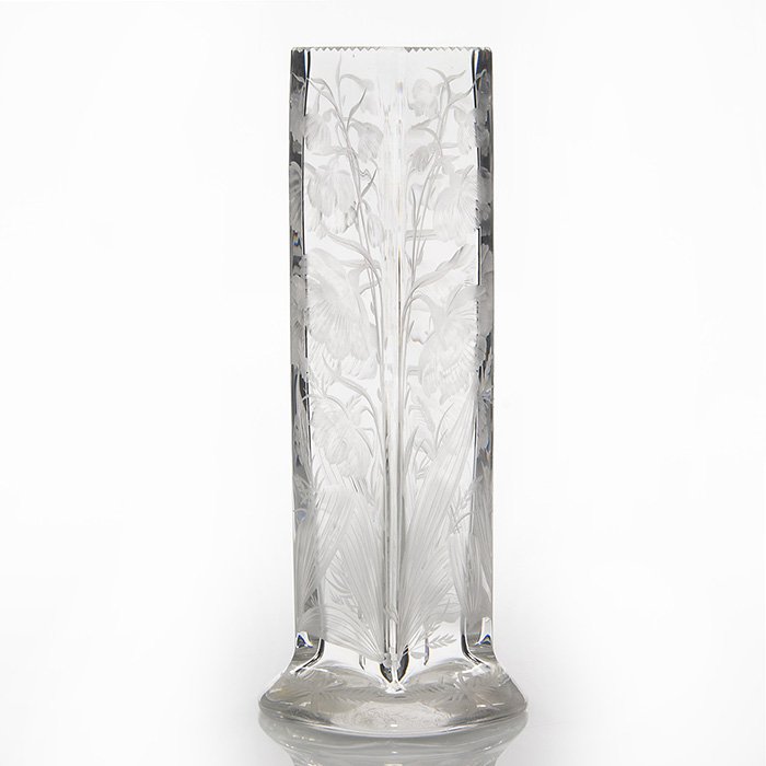 Libbey intaglio carved vase, floral, 11 3/4”, signed: Libbey four sided crystal vase intaglio carved with stalks of bowing flowerheads among striated leaf blades and seeding grasses. The flaring base is engraved with bows on fern fronds, the rim neatly n