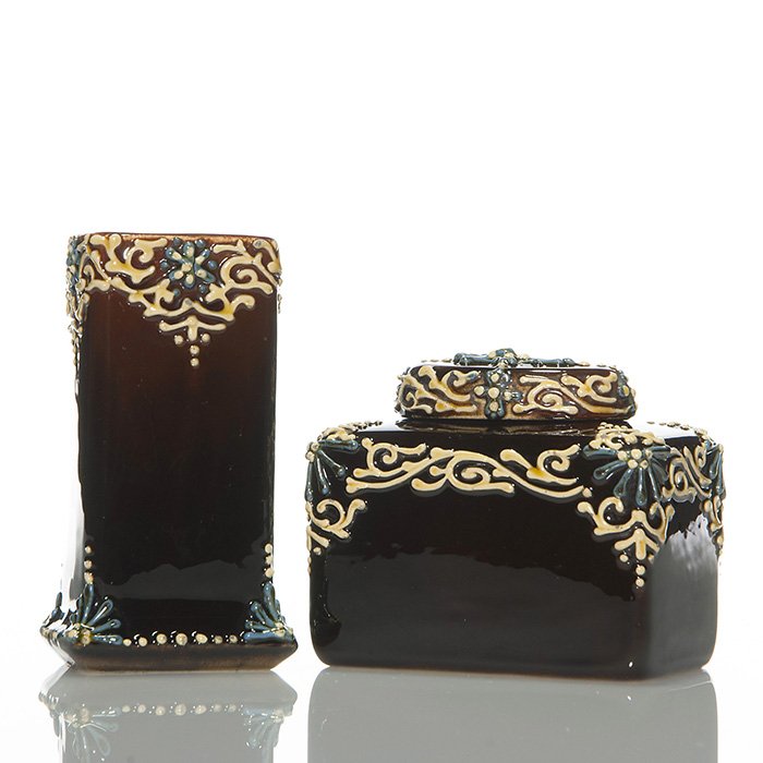 2 Owens Cyrano: 3 1/2”X4” covered box, 4 1/2” vase: Two Owens Cyrano items with ivory and blue applied design. First a covered rectangular container measuring 3 1/4 inches by 3 7/8 inches. Impressed with the company logo and an obscure number. Second a