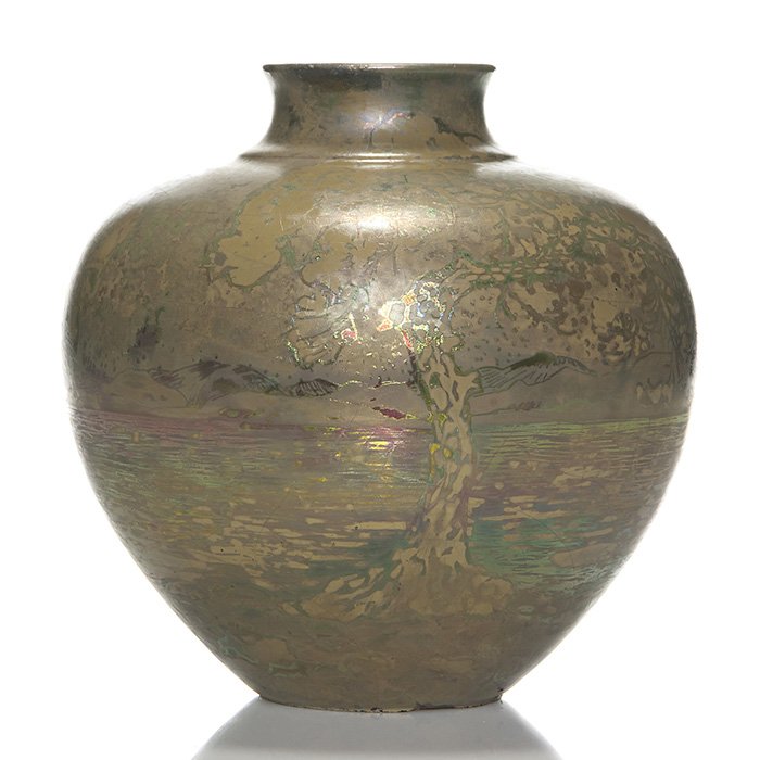 Massier scenic iridescent vase, trees, water, 7 3/4”: Massier scenic iridescent vase displaying large foliaged trees on the banks of a lake with foothills on the horizon. Measures 7 3/4 inches by 8 inches across. Marks in luster “Clement Massier, Golfe