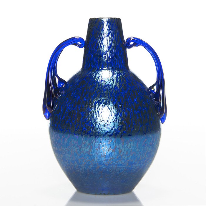 Loetz Czech cobalt Papillion handled vase, 7 7/8”: Loetz Czecho-Slovakia cobalt “Papillion” bottle vase adorned with cobalt reeded fleur-de-lis scroll handles. Height 7 7/8 inches. Oval acid stamp logo reads “Czecho-Slovakia” beneath. Beautifu
