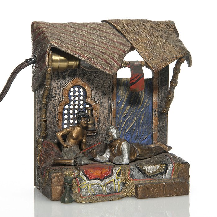 Austrian bronze lamp, 6 1/4” X 5 1/4”, marks: Vienna bronze figural cold painted “Arabian” lamp displaying a woman and man lounging on their front porch beneath a carpet overhang. Measures 6 1/4 inches by 5 1/4 inches across. Marked with a ra