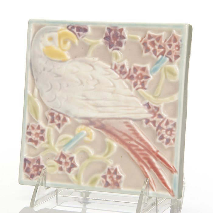 Rookwood Parrot trivet, 1930, shape 3077, 5 5/8”: Tea Tile featuring a parrot seated on a branch, decorated in a multitude of colorful mat glazes, pressed in 1930. Marks include the Rookwood logo, date, shape 3077 and a fan shaped esoteric mark. Uncr