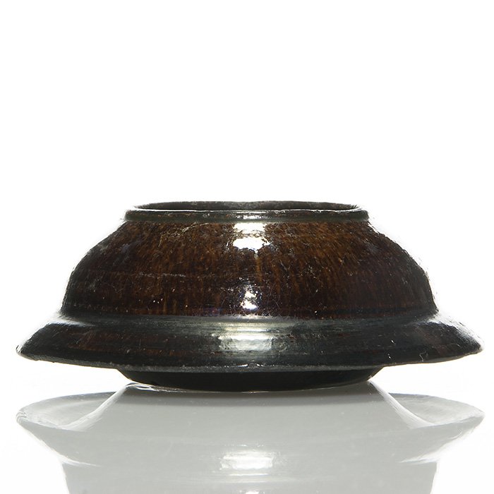 George Ohr low bowl, 2 by 5 1/2”: Decidedly untortured George Ohr low bowl done in dark brown and black shades. Impressed “Geo E. Ohr Biloxi, Miss.” on the bottom. Height is 2 inches and width is 5 1/2 inches. Roughness around the