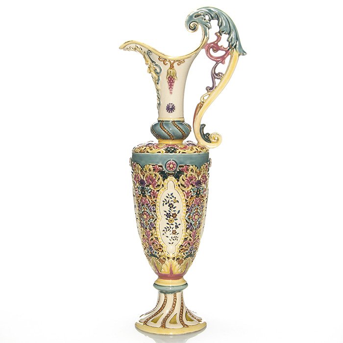 Early Zsolnay reticulated ewer, 19”: Tall and early Zsolnay ewer with floral decoration and reticulation. The face of a bewishered man is seen under the spout. Impressed Zsolnay Pecs 4665 and marked with the early Zsolnay ink stamp logo