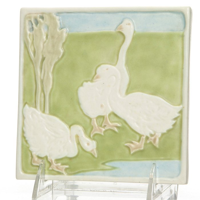 Rookwood 3 Goose tea tile, 5 1/2” square, 1943: Footed tea tile showing a gaggle of geese standing in a meadow at the waters edge. Measures 7/8 inches by 5 1/2 inches square. Marked with company logo, 1943 date, 3207 shape and incised with an X pos