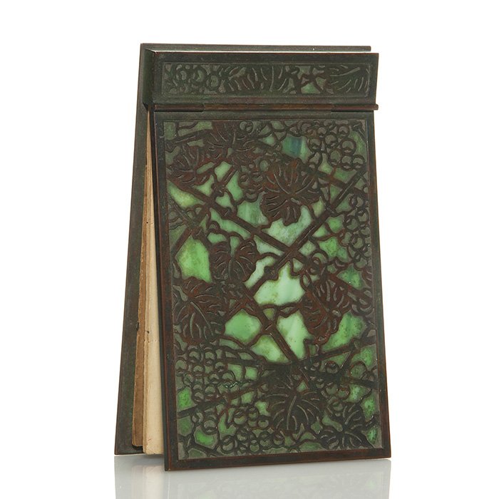 Tiffany Grape leaf hinged note pad holder: Large Tiffany bronze note pad holder with “Grape Leaf” pattern backed by green slag glass. Measures 7 5/8 inches by 4 5/8 inches. Impressed “Tiffany Studios, New York, 1022” on the back. Vinta