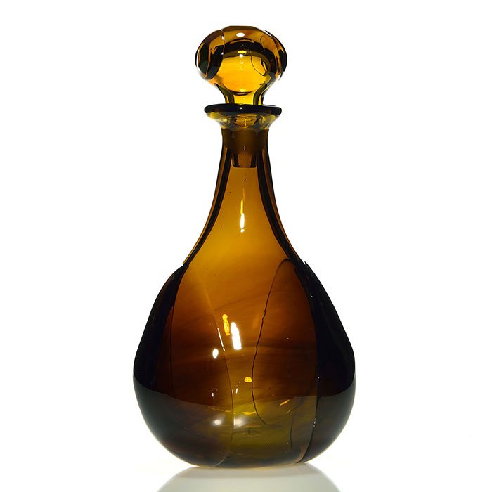 Dominic Labino Stoppered Bottle, 1968, 11": Dominick Labino spirit decanter with a hollow ball stopper. Created in dark amber, Labino perfectly fused prunts to each side of the bottle and the stopper, they taking on a slight opal blue tint at t