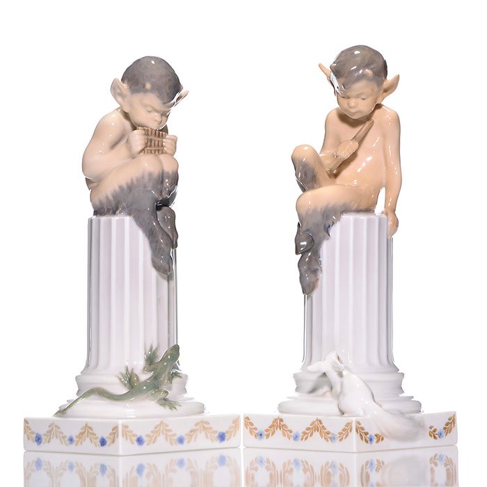 Pr Royal Copenhagen Pan on Pillars, 8 1/2": Pair Royal Copenhagen figurines by designer Christian Thomsen featuring mythical "Pan on Pillars" playing either flute or panpipes attracting a long eared squirrel or a lizard, circa 1953. Height 8 1/