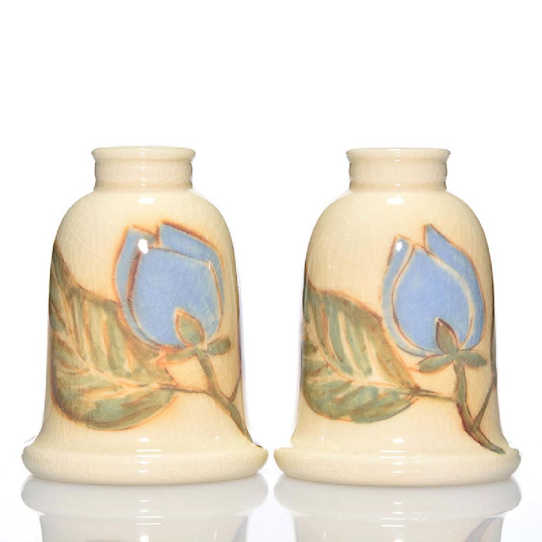 2 Rookwood glossy candleholders, Jensen, 4 3/8 inches: Design Crystal candleholders, each decorated with a single blue magnolia, the work of Jens Jensen in 1945. Marks include the Rookwood logo, date, shape 6913, the artist's cypher, a wheel ground X and 