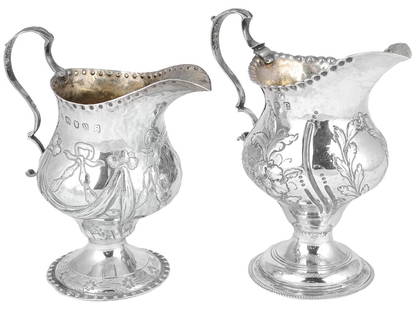 TWO GEORGE III SILVER MILK JUGS HESTER BATEMAN LONDON: TWO GEORGE III SILVER MILK JUGS HESTER BATEMAN LONDON 1776 AND 1785 on spreading circular bases the baluster bodies embossed with flowers or ribbon-tied festoons below punched lips leaf-capped double-