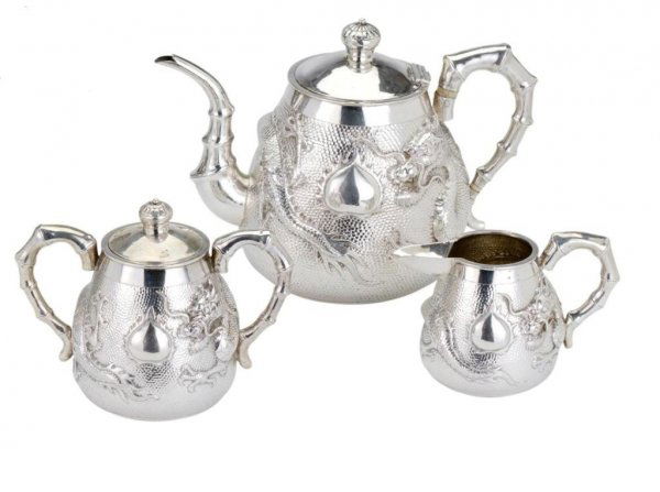 A CHINESE SILVER THREE-PIECE TEA SET, MAKER 'KH', S: A CHINESE SILVER THREE-PIECE TEA SET, MAKER 'KH', SHANGHAI, EARLY 20TH CENTURY tapering cylindrical, each chased with a dragon against a matted ground and applied simulated bamboo handles, the teapot