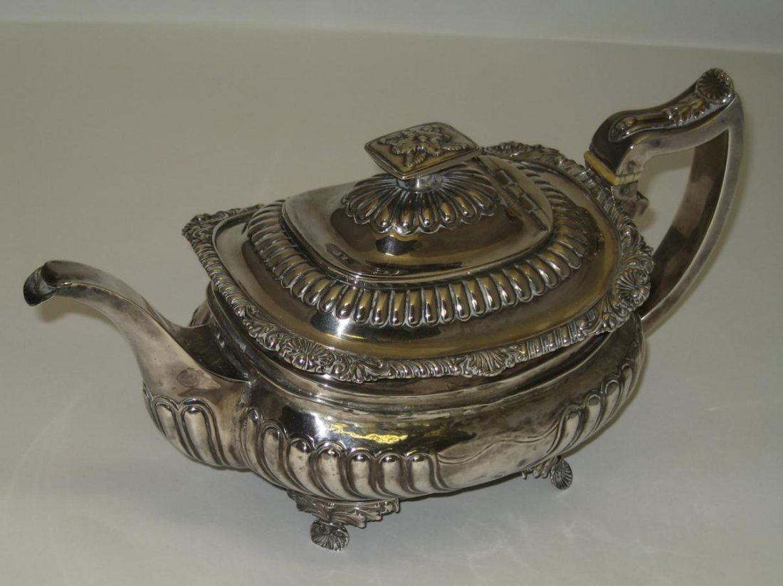 A GEORGE III SILVER TEAPOT, SARAH & JOHN WILLIAM B: A GEORGE III SILVER TEAPOT, SARAH & JOHN WILLIAM BLAKE, LONDON, 1818 oblong, embossed with lobes above shell and foliate supports, silver finial and handle 28.5cm long, 783gr (25oz) including ivory in