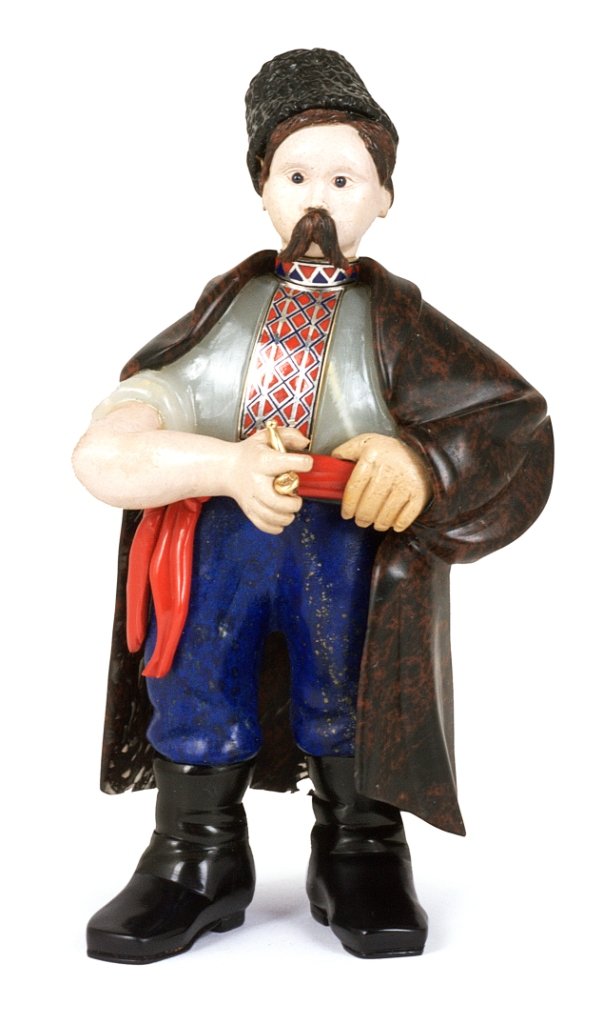 A RUSSIAN STYLE CARVED HARDSTONE FIGURE OF A UKRANIAN: A RUSSIAN STYLE CARVED HARDSTONE FIGURE OF A UKRANIAN PEASANT, AFTER KARL FABERGE, 20TH CENTURY wearing lapis trousers tied with a belt of purpurine, a mottled brown cloak of perhaps Urazov jasper dra