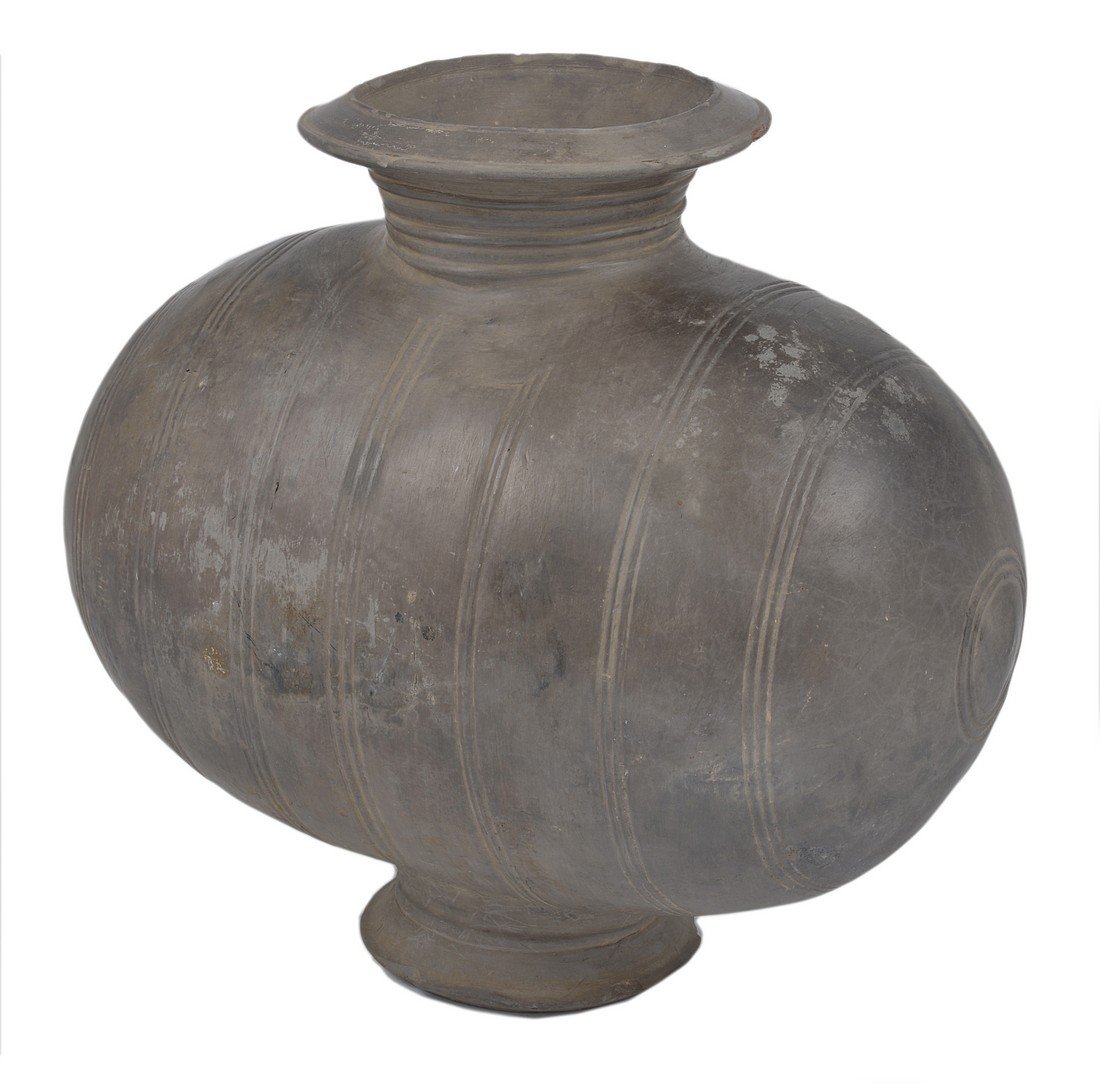 A CHINESE BURNISHED GREY POTTERY COCOON JAR, HAN: A CHINESE BURNISHED GREY POTTERY COCOON JAR, HAN DYNASTY (206 BC-220 AD) of elongated ovoid form with incised vertical triple bands, the neck with finely carved bands and lip, on a tall splayed foot 2