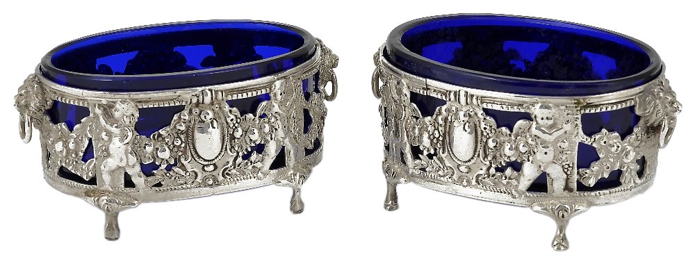 A PAIR OF GERMAN SILVER SALT CELLARS, CIRCA 1905 oval,: A PAIR OF GERMAN SILVER SALT CELLARS, CIRCA 1905 oval, pierced with cherubs holding foliate swags between lion masks and vacant ovals, Sterling import marked Faudell Philips & Sons, London, 1906, 9cm 