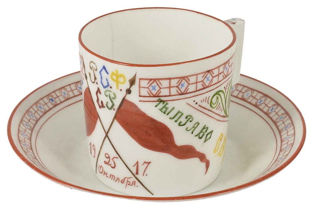 A SOVIET PROPAGANDA TEACUP AND SAUCER, BY THE IMPERIAL: A SOVIET PROPAGANDA TEACUP AND SAUCER, BY THE IMPERIAL PORCELAIN FACTORY, 1889, AND THE STATE PORCELAIN FACTORY, 1921 designed by Mikhail Mikhailovich Adamovich (1884-1947) in 1920, the cylindrical cu
