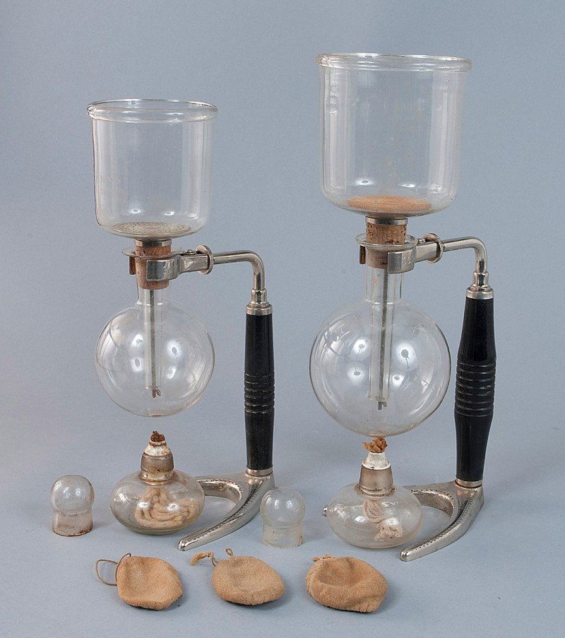 Two glass coffee makers, Art Deco. In various size: Two glass coffee makers, Art Deco. In various sizes, with corresponding oil lamps and glass tube holders, in the original box H = 28.0 D = 10.0 cm H = 24.0 D = 9.5 cm Zwei Glaskaffeemaschinen, Art Dec
