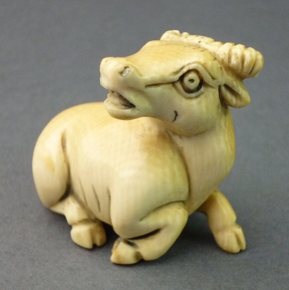 Netsuke, Kuh in sitzender Haltung, Mammutelfenbein,: Netsuke, Kuh in sitzender Haltung, Mammutelfenbein, Alterspatina, deutlich sichtbare Schregerlinien, bodenseitig signiert, Doppelbohrung, L= 4,0, H= 3,4cm