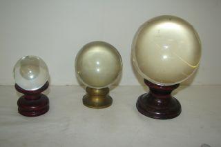 Group of 3 Crystal Balls 2 with wood base and one: Group of 3 Crystal Balls 2 with wood base and one with bras base . Measuring 6 1/4, 4 1/2" and 3 1/2". 2 with wood base and one with bras base . Measuring 6 1/4, 4 1/2" and 3 1/2".