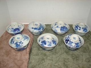 Oriental Blue & White Rice Bowls: Group of 7 bowls with covers. Group of 7 blue and white oriental rice bowls with lids. Each top and bottom is marked with characters in blue. Minor nicks on a couple bowls. . All different designs. Al