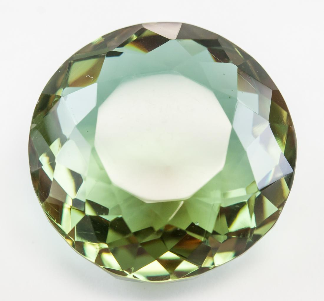 89.05ct Round Cut Brown to Green Alexandrite GGL: One (1) 89.05 ct round cut brown to green alexandrite. Origin: Brazil. Accompanied with GGL certificate. 28.22 x 26.32 x 17.03 mm.