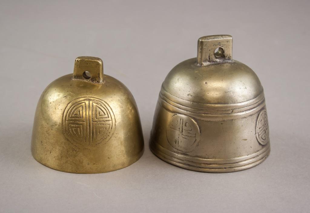 Pair of Chinese Bells Hand Made in Nepal: Pair of Chinese bells. Of brass tone. Stamped with circular design. Label reading "HAND MADE IN NEPAL" on one bell. Tongues attached inside with string. 6 x 8 cm. 474 grams (total).