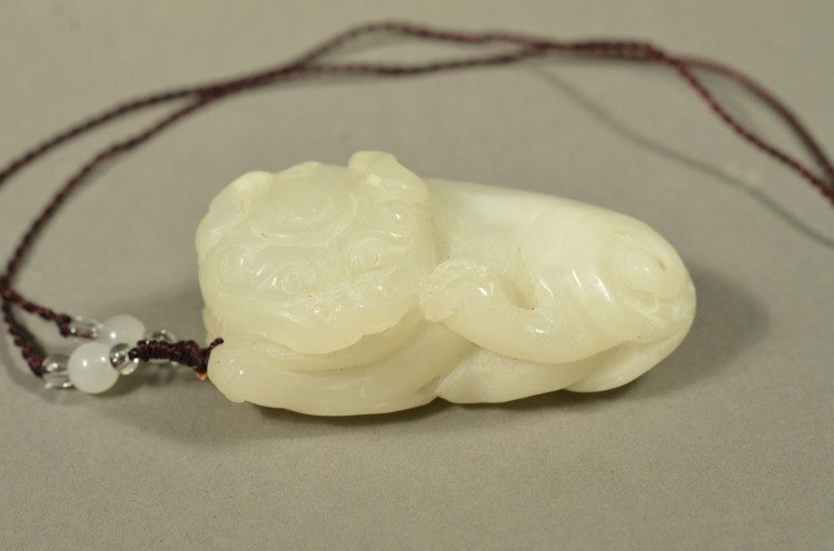 Chinese White Jade Fu Lion Holding Money Pendant: Chinese white jade pendant; fu lion in recumbent pose holding and cradling a coin; L: 6 cm, W: 4 cm, H: 3 cm, 78 grams
