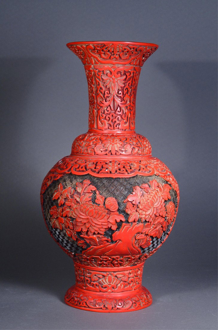 Chinese Carved Cinnabar Vase: Chinese cinnabar vase; featuring formalized lotus spray surrounded by carved classic scroll; lotus bloom enclosed within foliate cartouche on geometric lattice ground; flared neck featuring carved fol