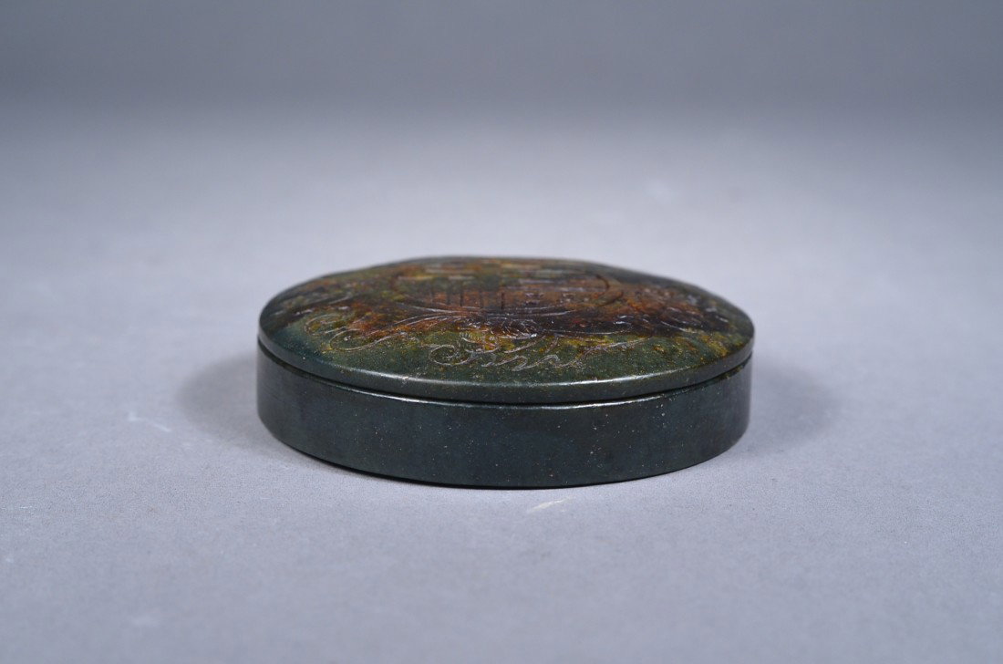 Chinese Spinach Green Jade Shou Cosmetic Box: Chinese carved cosmetic box; of cylindrical form, featuring four bats surrounding shou longevity roundel carved in shallow relief; the stone of spinach green tone with mottle brown suffusions; D: 8.5 