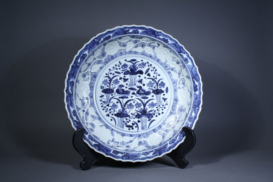 Chinese Qing Dynasty Foliate Rim Charger: Chinese Qing Dynasty blue and white porcelain charger; featuring central medallion of Mandarin ducks wading in pool with scroll design; the cavetto decorated with carved rose sprays borne on undulatin