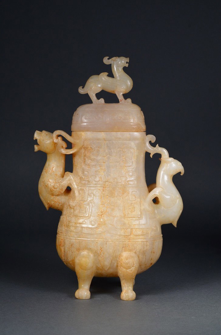 Chinese Ming Period Hu-Shaped Imperial Jade Vase: Archaistic Chinese Ming Period carved imperial white Hetian jade vase; hu-shaped with taotie-like masks on body with handles in form of mythical beasts in openwork; domed cover surmounted by Qilin fin