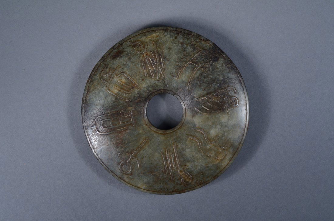 Large 10th Century Chinese Jade Bi Disc: 10th Century Chinese carved jade bi disc; featuring qilin and other mythical beasts in relief; ancient script characters, on verso; the stone of translucent green tone with grey suffusions; D: 14 cm,