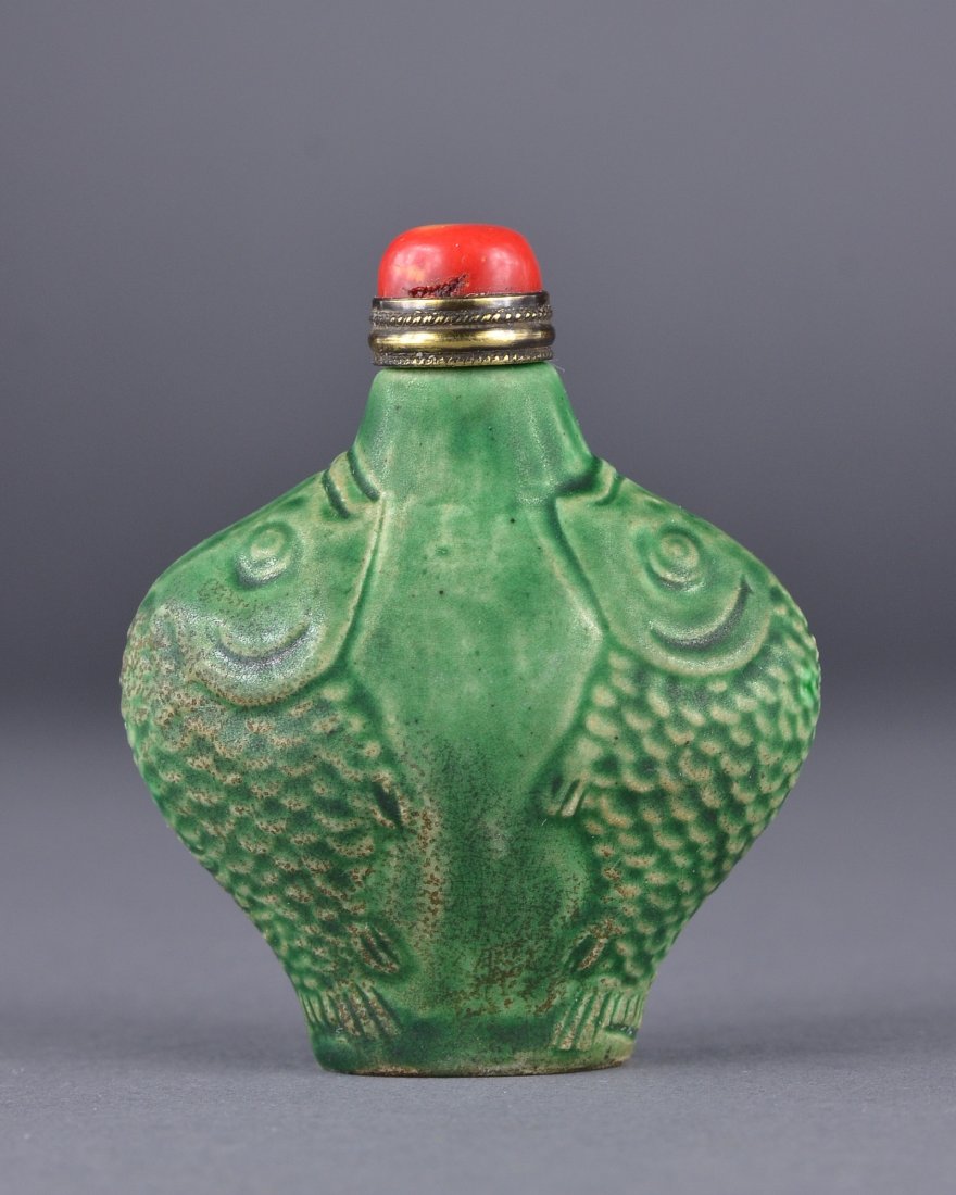 19th Century Chinese Green Glazed Snuff Bottle: 19th Century Chinese green glazed porcelain snuff bottle; ovoid tapering body featuring molded design of auspicious fishes; L: 7 cm, W: 5 cm, 63 grams