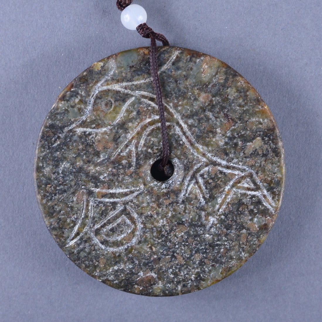 Archaic Chinese Han Dynasty Jade Pendant: Archaic Chinese Han Dynasty carved jade pendant; featuring mythical bird carved in relief; the stone of green tone with some calcification; D: 7 cm, 86 grams